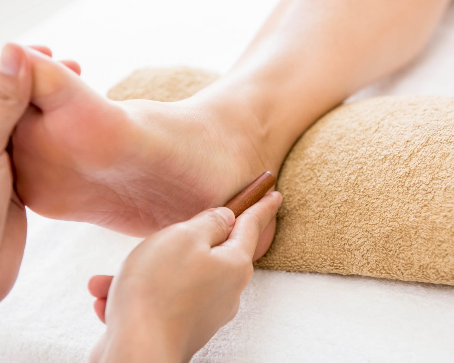 Professional therapist giving relaxing reflexology foot massage to a woman in spa