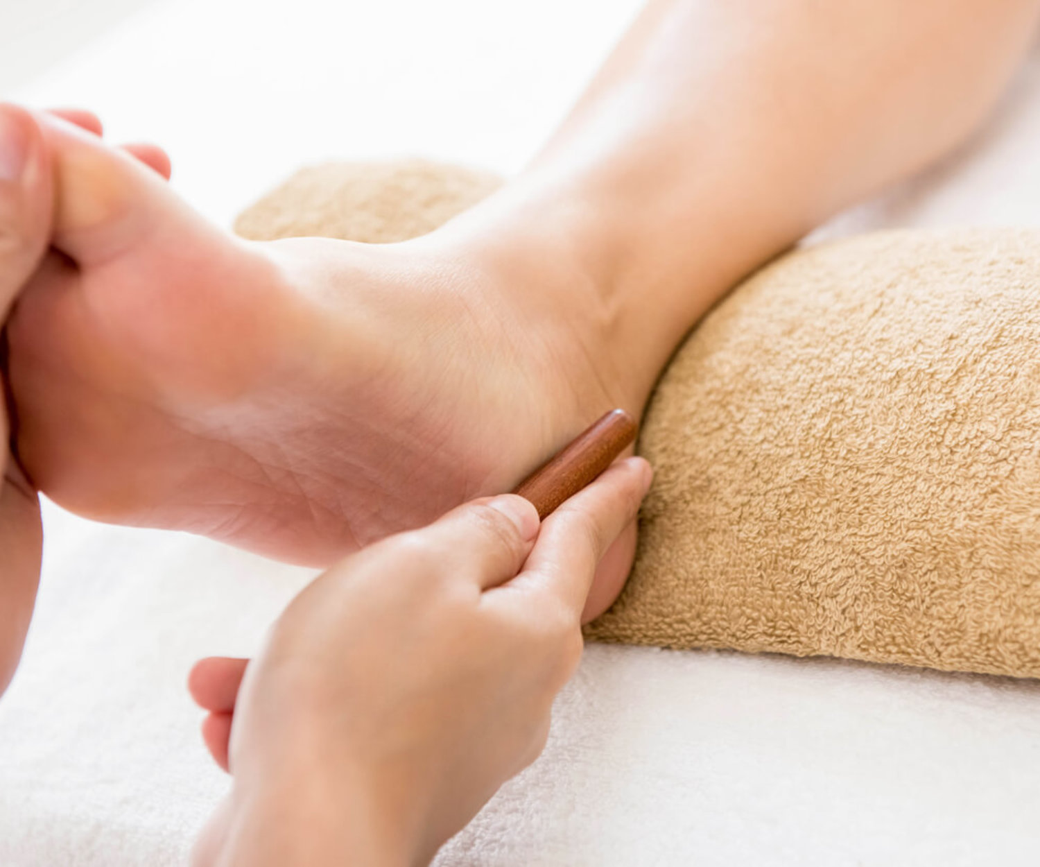 Professional therapist giving relaxing reflexology foot massage to a woman in spa