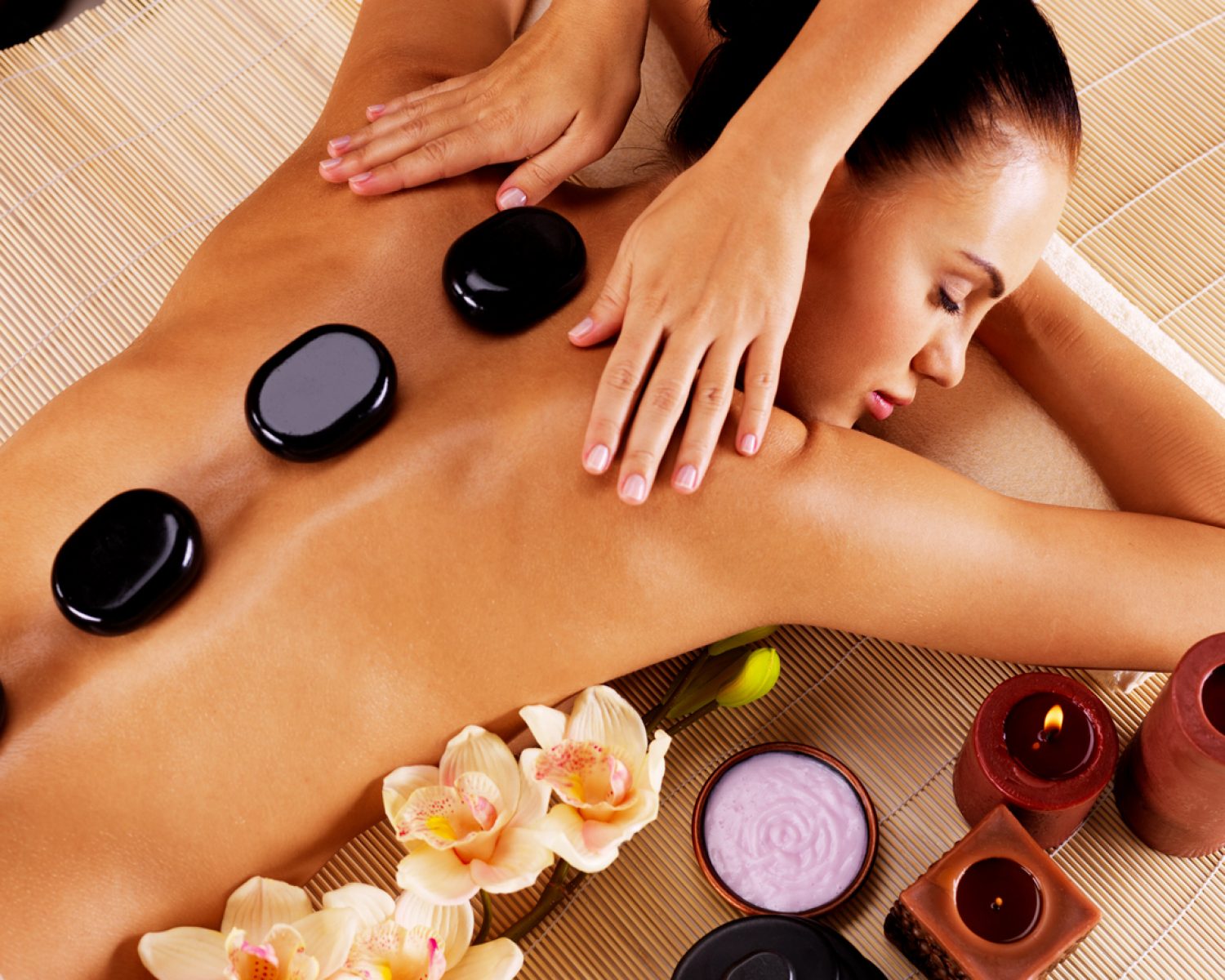 Adult woman having hot stone massage in spa salon. Beauty treatment concept.