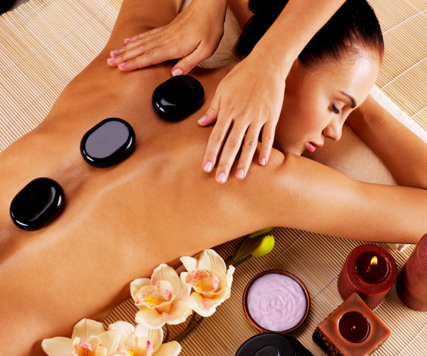 Adult woman having hot stone massage in spa salon. Beauty treatment concept.